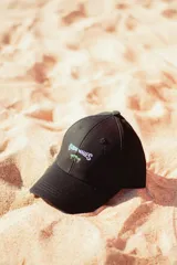 Gorra negra con bordado frontal de la marca "Glossy Waves" con palmeras.