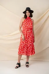 Vestido midi de gasa con seda, color rojo con lunares blancos, cuello halter, cintura elastizada con lazo y volado en el ruedo.