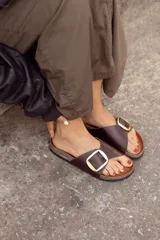 Sandalias de cuero color marrón con hebilla metálica plateada.