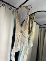 Vestido corto de encaje color crema, con escote halter y falda asimétrica con volados. Incluye short.