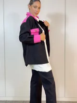 Sobre camisa negra con canesú, bolsillo y puños en color fucsia.