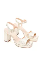 Sandalias doradas con plataforma y taco alto, tiras finas y hebilla lateral.