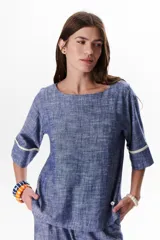 Blusa azul de lino con escote barco y mangas 3/4 con detalle de ribete blanco.