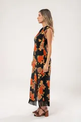 Vestido midi negro con estampado de flores naranjas y beige, espalda descubierta con tres botones en forma de flor, tajo lateral y flecos en el ruedo.