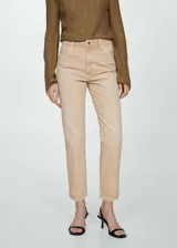 Pantalón de jean color beige, corte mom fit, tiro alto, cinco bolsillos y cierre con cremallera y botón.