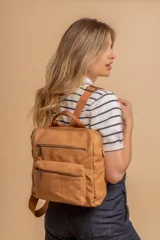 Mochila mediana de símil cuero color beige, con asa superior, dos compartimentos principales con cierre y dos bolsillos frontales con cierre. Las correas son ajustables y de color beige.