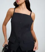 Chaleco femenino de sastrería color negro, con breteles finos y cierre frontal de botones. Diseño alargado con bolsillos falsos en la parte inferior.