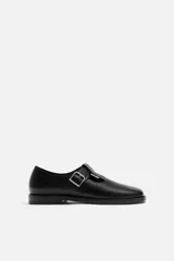Zapato tipo Mary Jane de cuero negro con hebilla lateral, horma redonda y suela con ligero tacón.