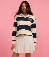 Suéter slim con cuello polo, manga larga y rayas horizontales en tonos crema y azul marino. Presenta lettering "NYC" bordado en el pecho y está confeccionado en algodón con forro fleece.