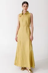 Vestido largo color amarillo mostaza, sin mangas, con cuello camisero, cierre frontal con cremallera y corte evasé.