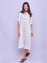 Vestido camisero largo de lino color beige, con cuello clásico, manga larga con puños abotonados y cierre frontal con botones. Tiene un bolsillo de parche en el pecho.