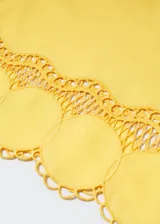 Blusa amarilla corta con cuello redondo, mangas cortas acampanadas y detalle de bordado calado en el ruedo.