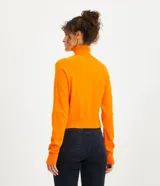 Blusa de punto color blanco, con cuello alto, manga larga y diseño liso.