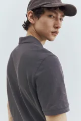 Remera polo gris de piqué de algodón, de manga corta, con cuello clásico, tapeta de botones, remate acanalado en cuello y mangas, bajo recto con aberturas laterales y corte estándar.
