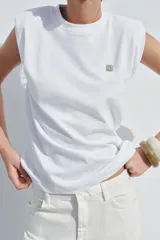 Camiseta blanca de algodón con cuello redondo y manga sisa con hombreras. Detalle de aplicación metálica ZA en el delantero.