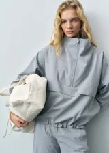 Anorak gris con cuello chimenea, diseño oversize y cierre de cremallera en el cuello.