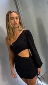 Vestido corto negro con lurex, de un hombro, con manga larga abullonada y abertura en la cintura.