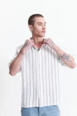 Camisa de manga corta con corte oversize, a rayas verticales blancas y grises, con cuello clásico y cierre frontal con botones. Confeccionada en algodón.