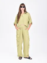 Camisa negra de manga corta con cuello camisero y botones frontales. Presenta un corte cropped y textura acanalada o plisada.