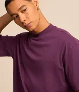 Remera blanca de algodón, corte holgado, cuello redondo alto, manga corta y sisas caídas.