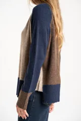 Sweater de tejido de punto con diseño color block. Cuerpo principal en beige jaspeado, mangas y puños en azul marino, y detalles en marrón en el cuello y puños.