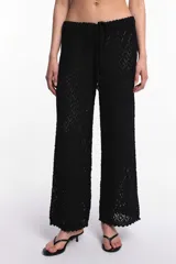 Pantalón blanco de tejido calado con cintura elástica y cordón ajustable.