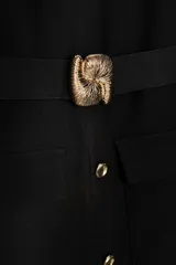 Vestido midi negro sin mangas, con cuello redondo, cinturón con hebilla metálica y cierre frontal con botones.