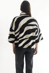 Sweater color crema con cuello alto y mangas cortas anchas, con diseño de cuadros negros.
