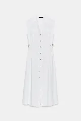 Vestido midi blanco, sin mangas, con cuello solapa, escote pico y cierre frontal de botones. Presenta falsos bolsillos con solapas en el pecho y trabillas con hebillas ajustables en la cintura.