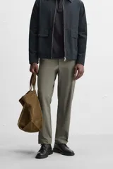 Pantalón chino negro slim fit confeccionado en tejido técnico de secado rápido. Cuenta con bolsillos frontales y traseros de vivo. Cierre frontal con cremallera y botón.