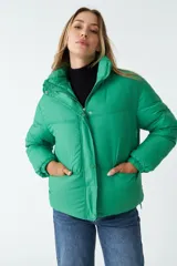Campera puffer lila de nylon con cuello alto, cierre frontal con cremallera y bolsillos laterales con cierre.