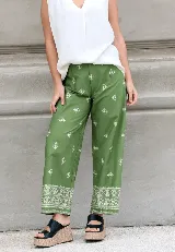 Pantalón verde con estampado de flores blancas, corte recto, con pinzas frontales, bolsillos traseros y cintura elástica.