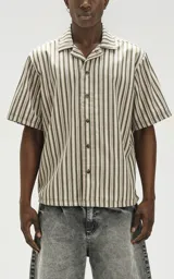 Camisa oversize de manga corta con cuello abierto y estampado a rayas verticales en tonos verde y beige.
