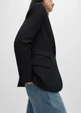 Blazer negro de corte recto con cuello de pico con solapa, tres bolsillos de solapa en la parte frontal y manga larga con puños abotonados.