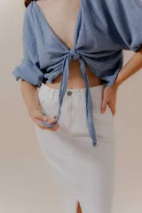 Falda midi de denim blanco, tiro alto, con abertura frontal pronunciada.