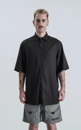 Camisa negra de manga corta con cuello clásico y cierre frontal con botones.