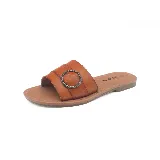 Sandalia baja color marrón con tira ancha sobre el empeine y hebilla circular decorativa.