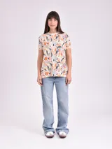 Remera estampada con motivos florales en tonos naranja, beige, gris y rosa.