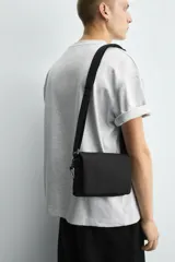 Bandolera negra de nylon con solapa y cierre magnético. Tiene correa ajustable con mosquetón y bolsillo interior.