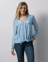 Camisa de gasa celeste con estampado de rayas verticales en tonos azules, rosas y verdes. Tiene cuello con solapa, escote en V, abertura central con botones, bolsillo aplicado en el pecho y terminación anudada en la parte delantera.