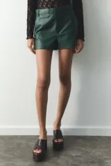 Shorts de tiro alto color borgoña, con bolsillos delanteros y cierre frontal con cremallera y ganchos metálicos.