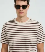 Remera de manga corta con cuello redondo y corte regular. Diseño a rayas horizontales en color marrón sobre fondo beige.