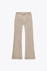 Pantalón de jean color beige, de tiro alto, corte ajustado en la cadera y muslos, y acampanado desde la rodilla. Tiene cinco bolsillos y cierre frontal con cremallera y botón.