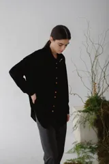 Camisa beige de terciopelo con cuello clásico, cierre frontal con botones, dos bolsillos de parche en el pecho y mangas largas con puños abotonados.