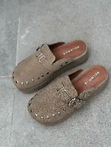 Zuecos color beige de gamuza con detalle de tachas y hebilla metálica.