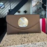 Sobre de fiesta color marrón, hecho artesanalmente en la India, con aplique de piedra ágata a tono. Incluye asa de cadena para llevar al hombro.