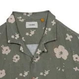 Camisa de manga corta color verde con estampado de flores abstractas en color beige. Presenta cuello tipo resort, cierre frontal con botones y un diseño de calce relajado. Marca Critical Slide, modelo Splatter Resort.
