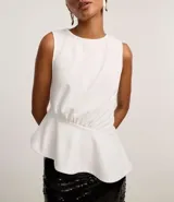 Blusa peplum blanca sin mangas con cuello redondo y ruedo asimétrico.