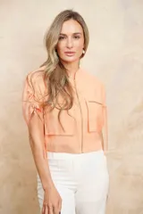 Chaqueta bomber corta color verde agua, con cierre frontal dorado, bolsillos grandes con cierre y mangas cortas ajustables con lazos.