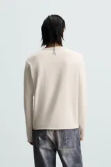 Camiseta color beige de corte relaxed fit, con cuello redondo y mangas largas combinadas con tejido de red.